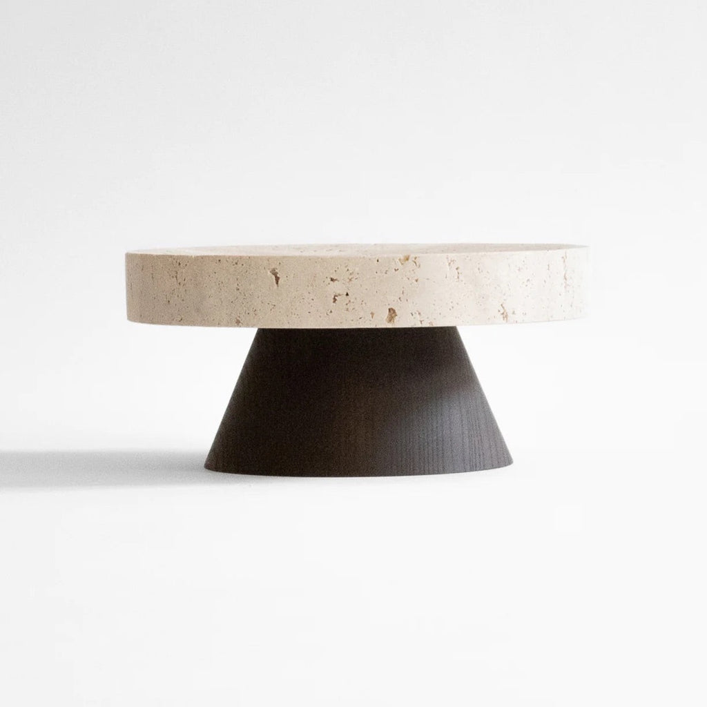 A round coffee table with a black base, showcasing architectural heritage with ORIGIN MADE's COLISEU PEDESTALS.