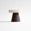 A round table with a wooden top supported by Coliseu Pedestals, combining architectural heritage and Origin Made craftsmanship, featuring a black base.