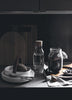 A black and white photo of a kitchen with a COZY coffee jar, plates and utensils.