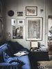 A living room with a blue HAPPY HOMES CREATIVE couch and framed pictures.