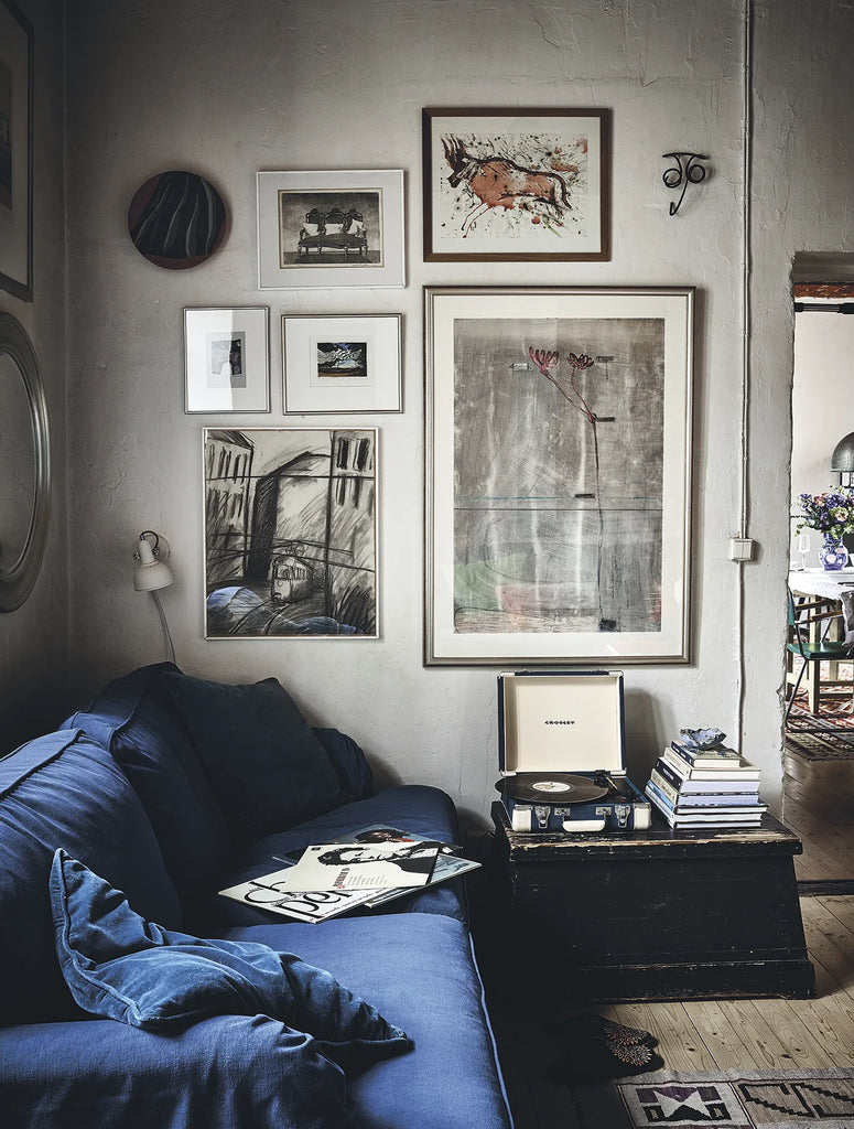 A living room with a blue HAPPY HOMES CREATIVE couch and framed pictures.