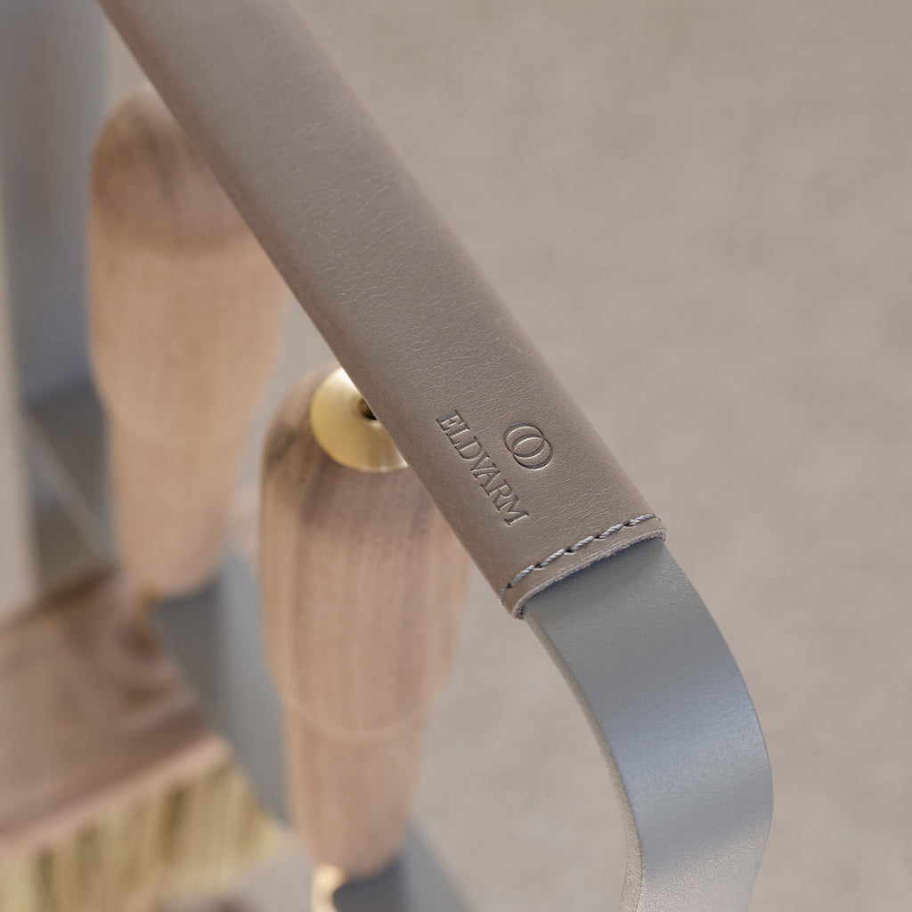 Close-up of a leather-wrapped handle on the metallic EMMA FIRE TOOL COMPANION SET by ELDVARM, embossed with "LUXURY," featuring wood and brass accents—an elegant upgrade for any fireplace tool set.