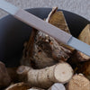 An EMMA WOOD BASKET with logs in it and a knife in it.