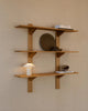 The Danish-designed wooden wall shelves display books, decorative plates, and the sleek FUTÉ Table Lamp by LYFA for an elegant look.