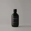 A bottle of Manisante Oud Shampoo for gentle cleansing on a grey background.