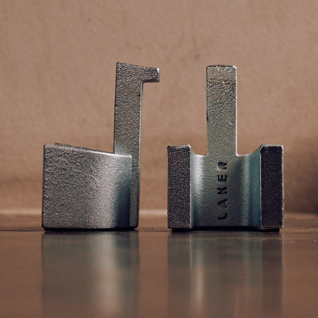 Two LAKER STUDIO cast iron LUG DOORSTOPS sitting on a table next to each other.