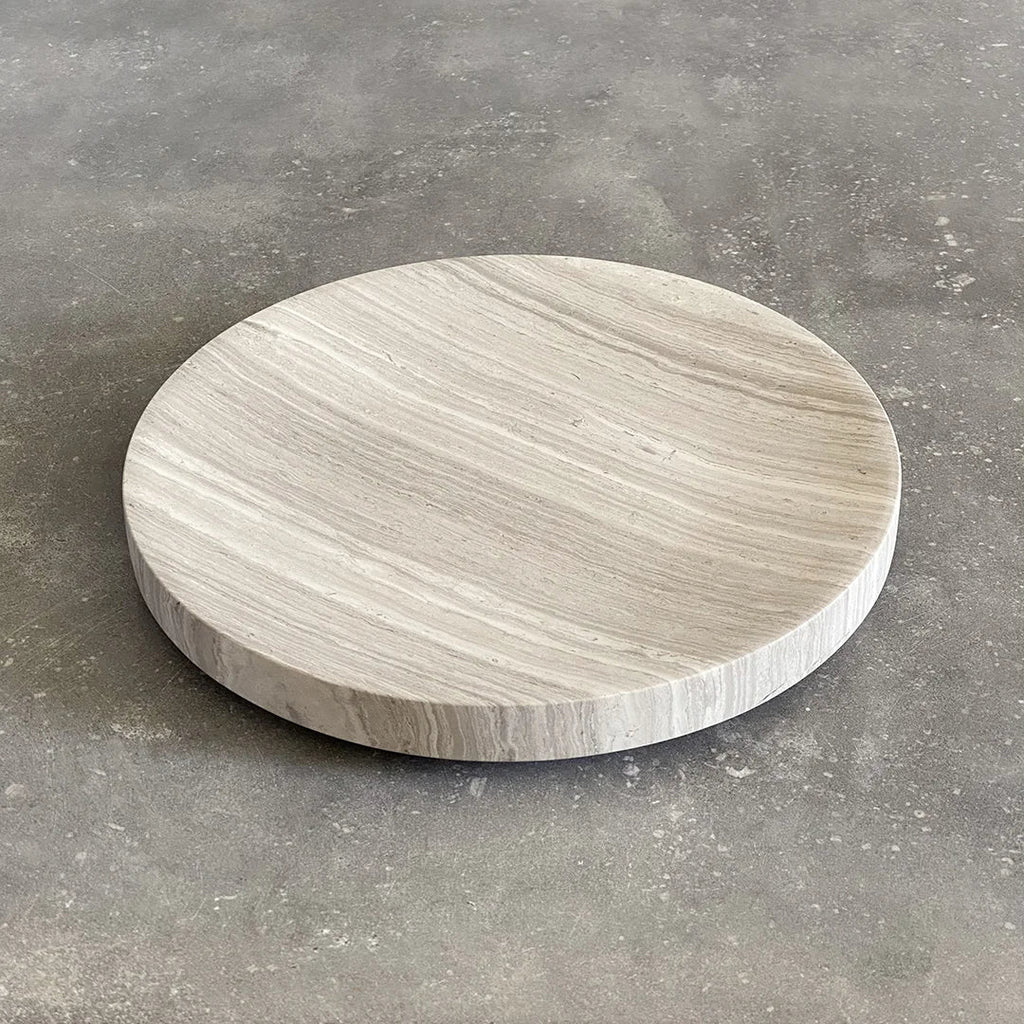 A round white SABI BOWL plate on a concrete floor by BRANDT COLLECTIVE at Gestalt Haus.