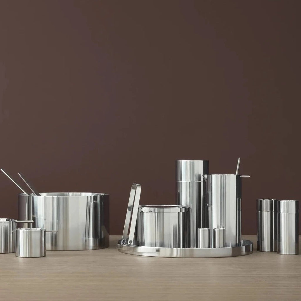 A set of STELTON pots and pans on a wooden table by ARNE JACOBSEN SERVING TRAY.