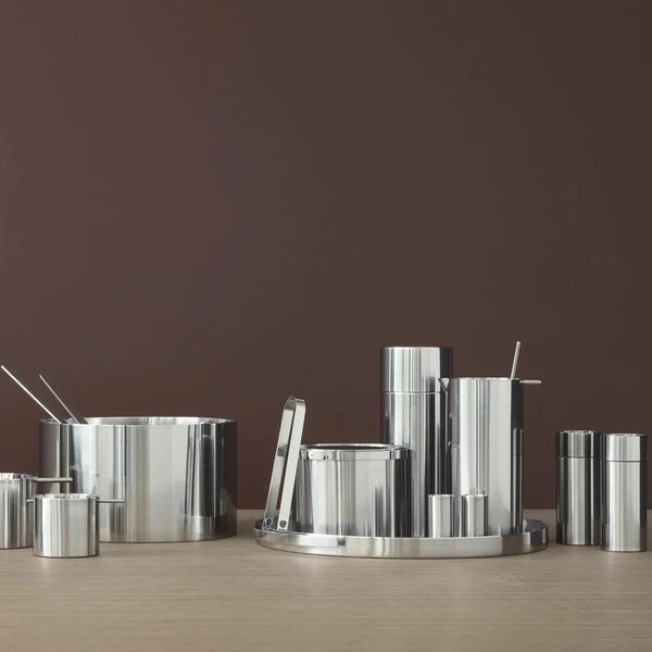 A set of STELTON pots and pans on a wooden table by ARNE JACOBSEN SERVING TRAY.