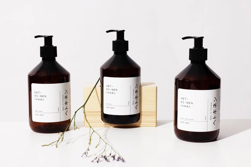 Three HETKINEN hand soap bottles on a wooden table.