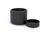A black BOTANY PORCELAIN PLANT POT by AARON PROBYN and a black bowl on a white surface in the Gestalt Haus.