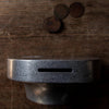 A COINK PIGGY BANK BOOKEND by STUDIO HENRY WILSON sits on top of a wooden table in Gestalt Haus.
