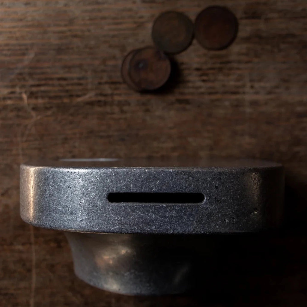 A COINK PIGGY BANK BOOKEND by STUDIO HENRY WILSON sits on top of a wooden table in Gestalt Haus.