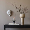 A DREAMER SCULPTURE by COOEE with a candle on a table next to a Gestalt Haus wall.