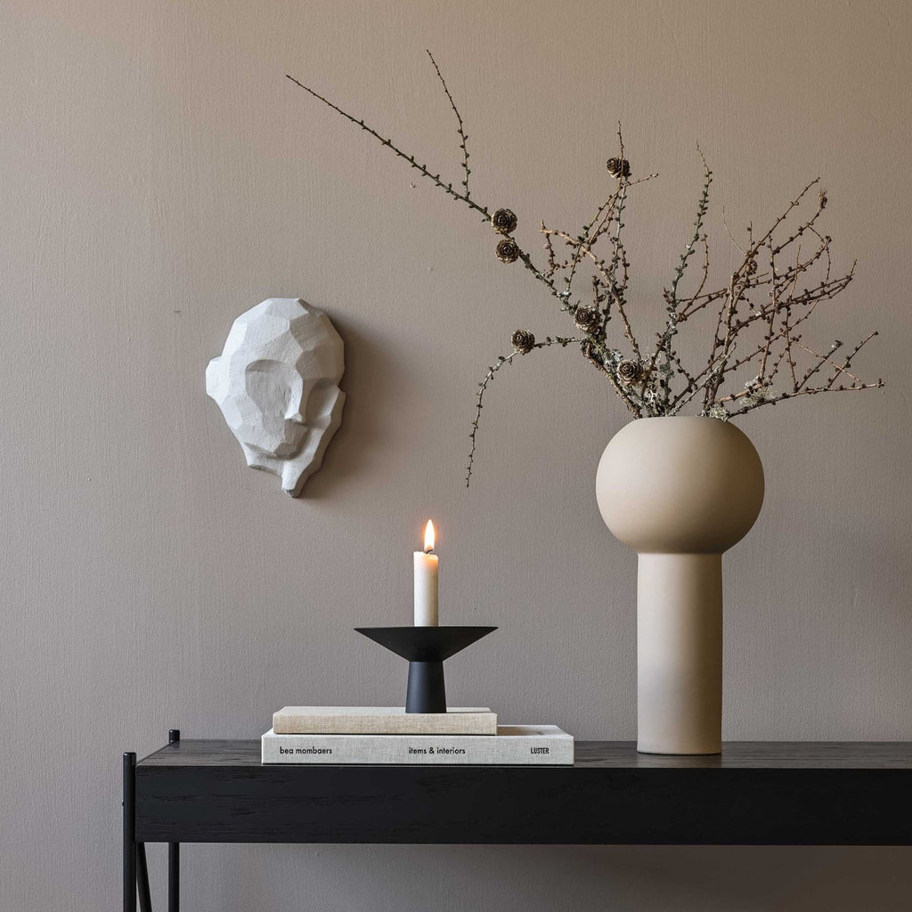 A DREAMER SCULPTURE by COOEE with a candle on a table next to a Gestalt Haus wall.