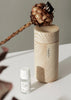 A Hetkinen wooden container with a Gestalt Haus flower and a bottle of Drop Oil Diffusers essential oil.
