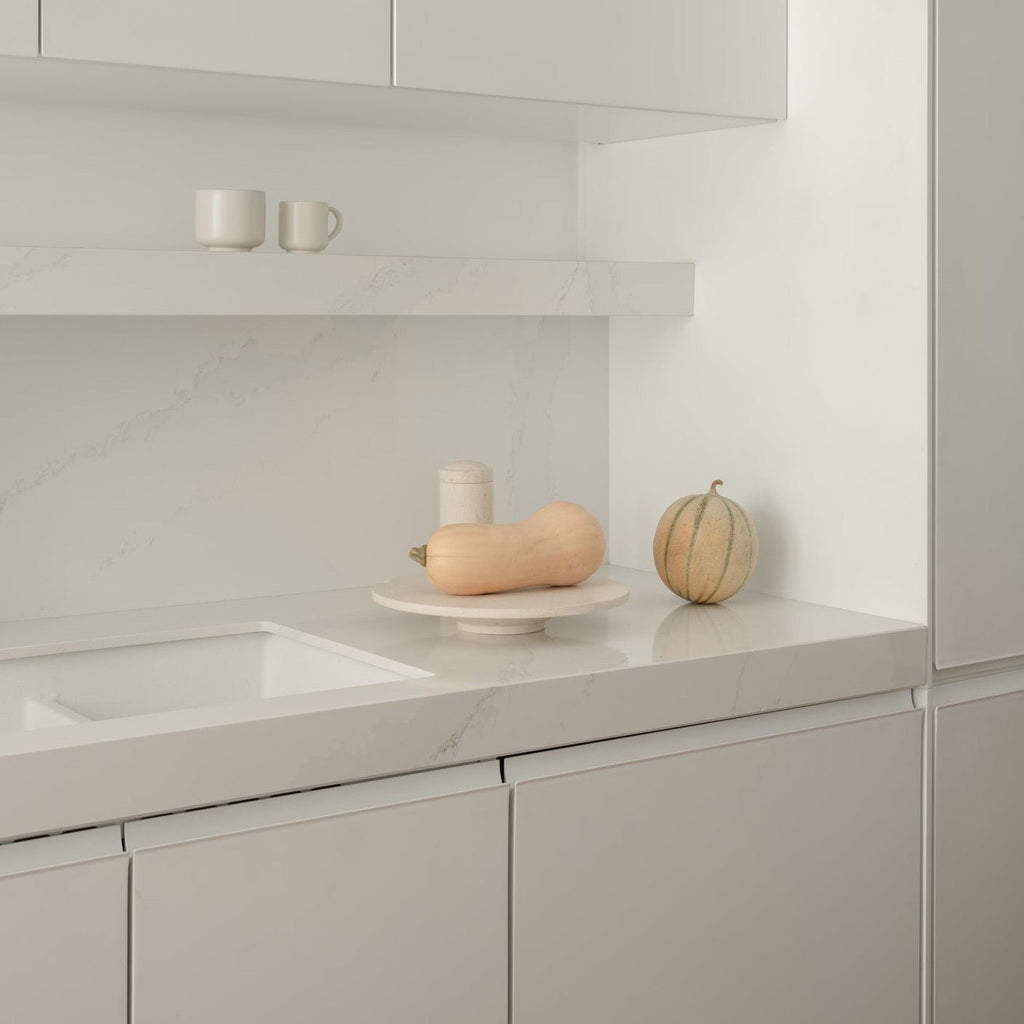 A white kitchen with white cabinets and a Louise Roe Gallery Object Cake Stand embodies the sleek elegance of Gestalt Haus.