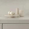 A white GALLERY OBJECT CAKE STAND by LOUISE ROE adorned with a bowl of onions and a bowl of olives at Gestalt Haus.