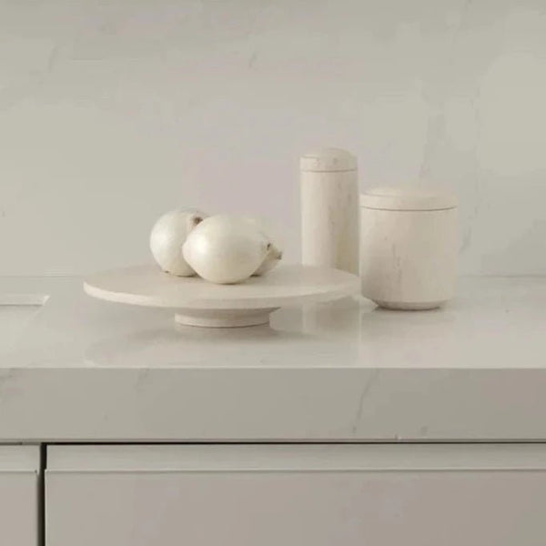 A white GALLERY OBJECT CAKE STAND by LOUISE ROE adorned with a bowl of onions and a bowl of olives at Gestalt Haus.