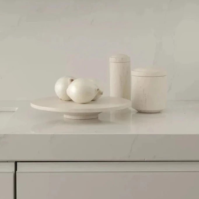 A white GALLERY OBJECT CAKE STAND by LOUISE ROE adorned with a bowl of onions and a bowl of olives at Gestalt Haus.