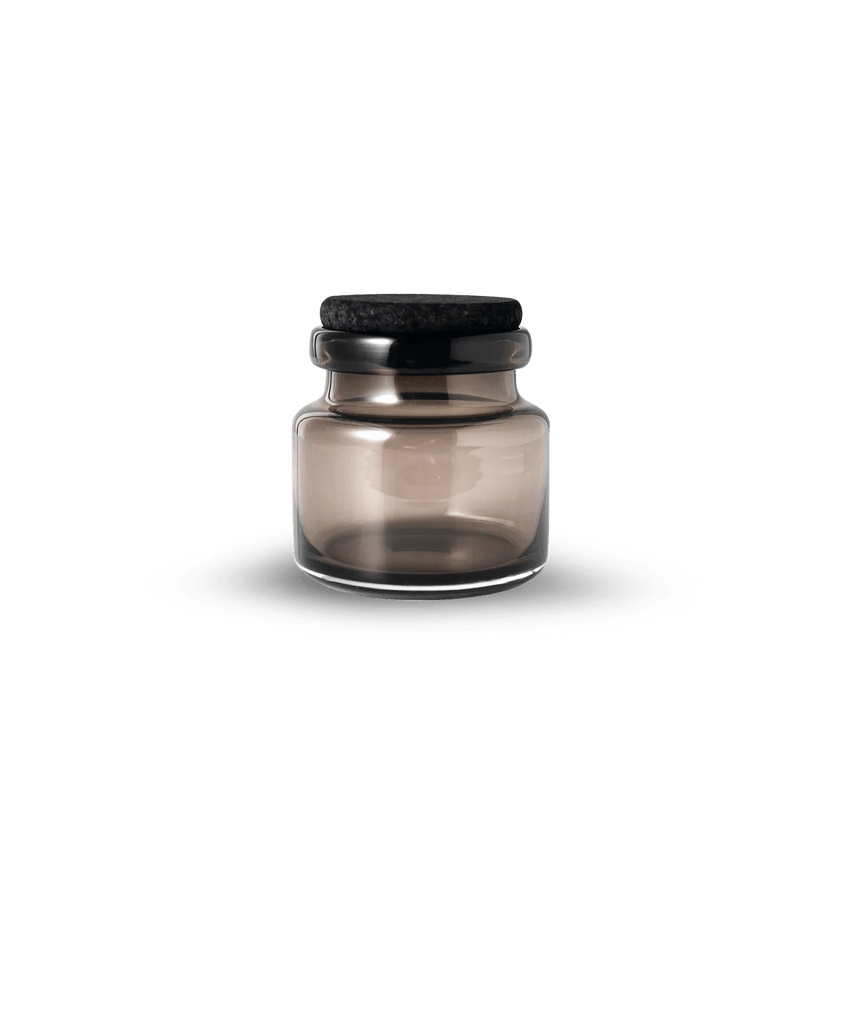 A Louise Roe glass jar with a black lid on a white background, inspired by the minimalist essence of Gestalt Haus.
