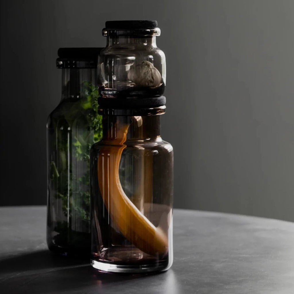 Two Louise Roe glass containers of herbs on a table at Gestalt Haus.