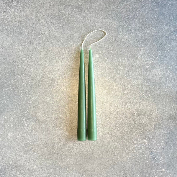 Two DANICA DESIGNS HAND-DIPPED TAPER CANDLES adorned in a Gestalt Haus, hanging on a wall.