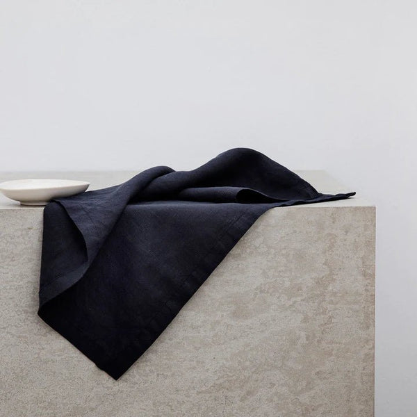 A black CULTIVER LINEN NAPKIN placed atop a concrete table at Gestalt Haus.