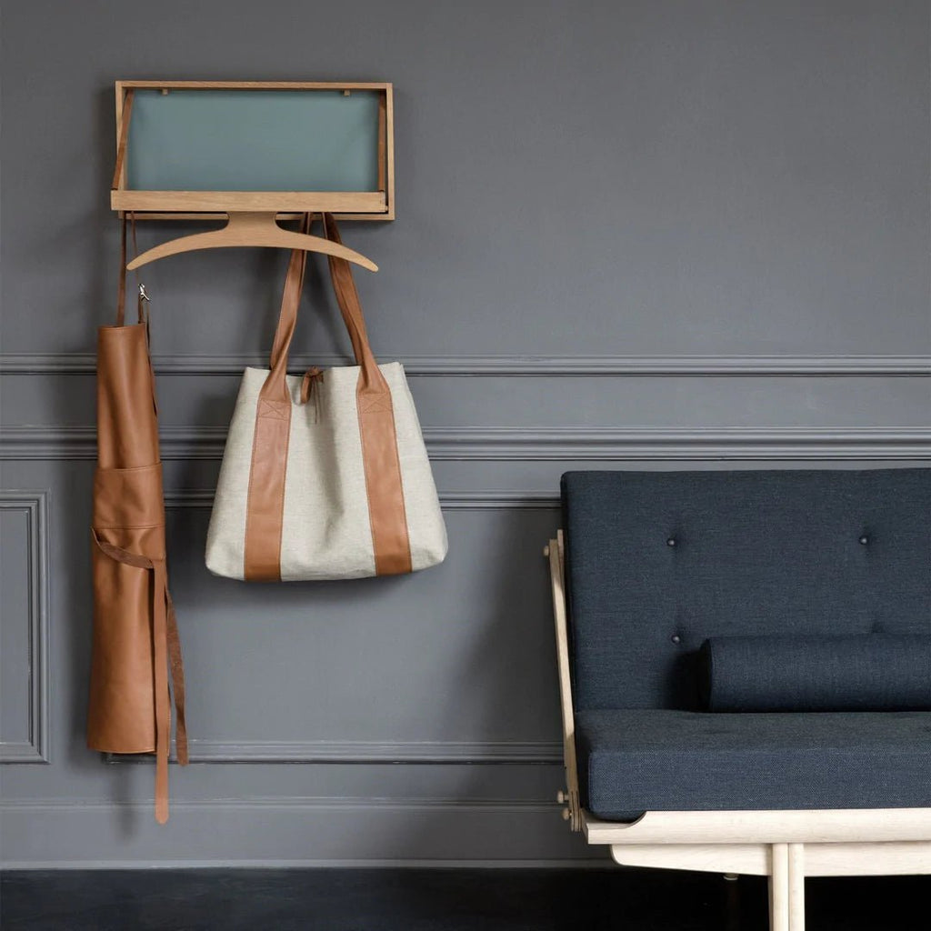 A KLASSIK STUDIO coat rack hanging on a Gestalt Haus wall next to a couch.