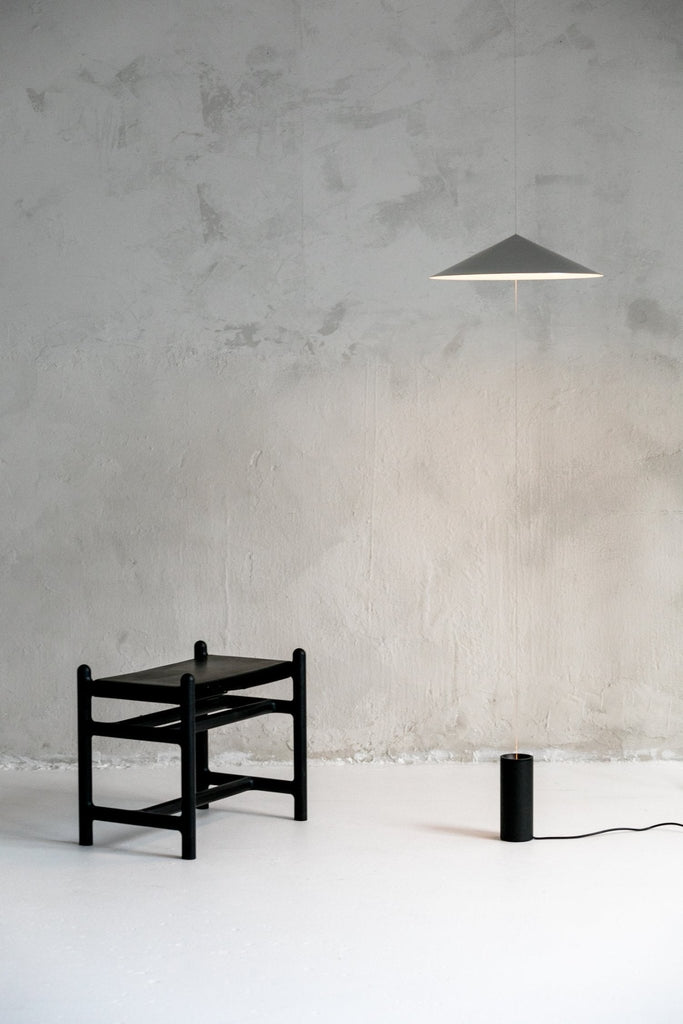 A black THE WISP LAMP with a stool next to it, designed by ANONY and inspired by Gestalt Haus.